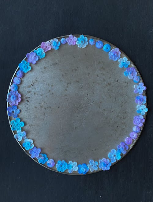 A round mirror with blue and purple flowers on it