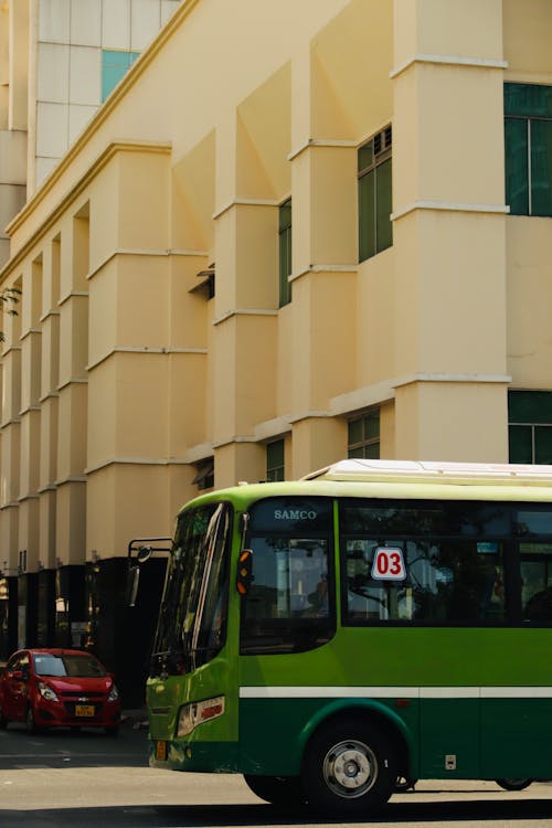 A green and white bus driving down a street