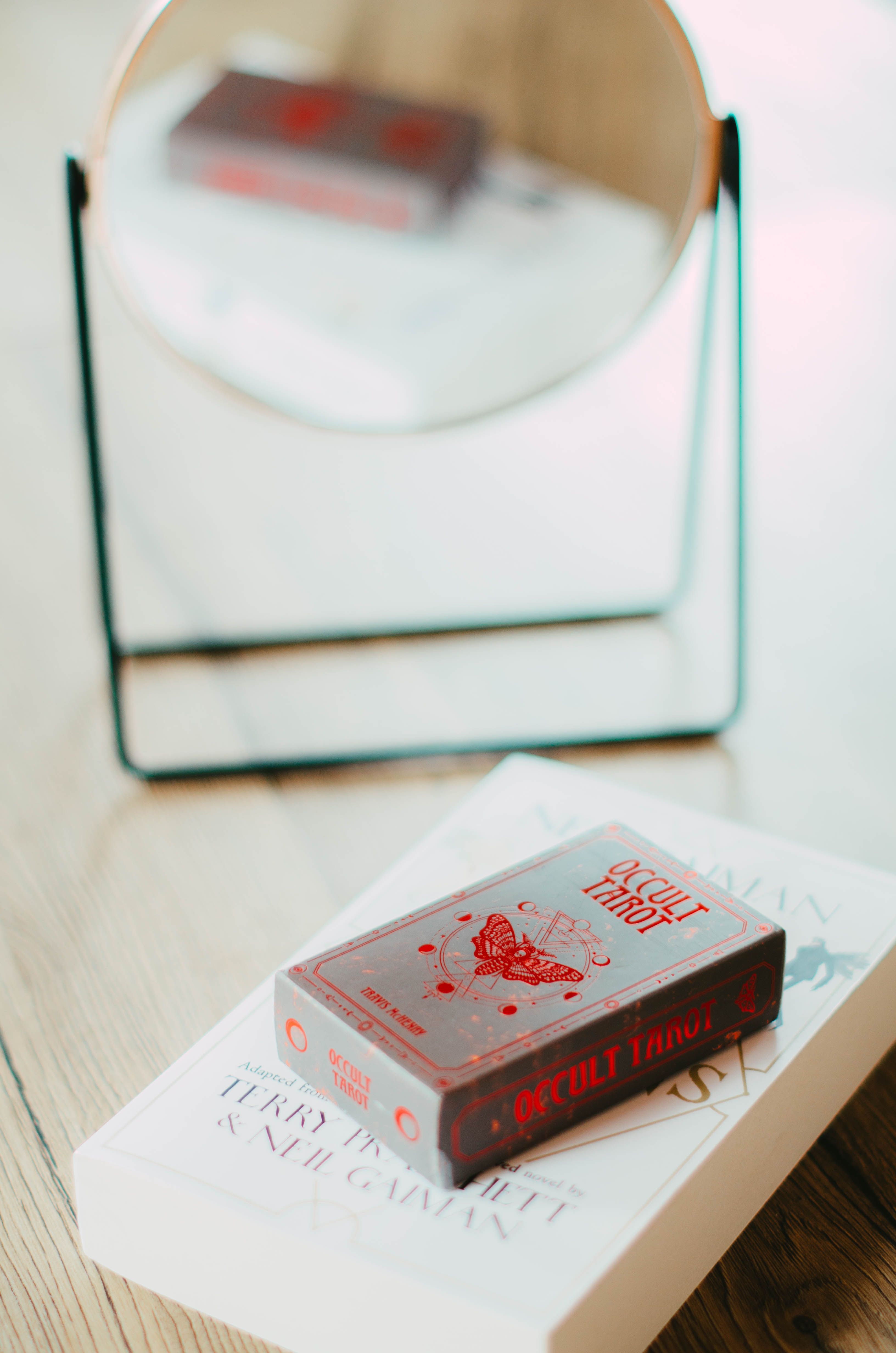 Tarot deck on a book, reflected in a mirror, creating a mystical ambiance.