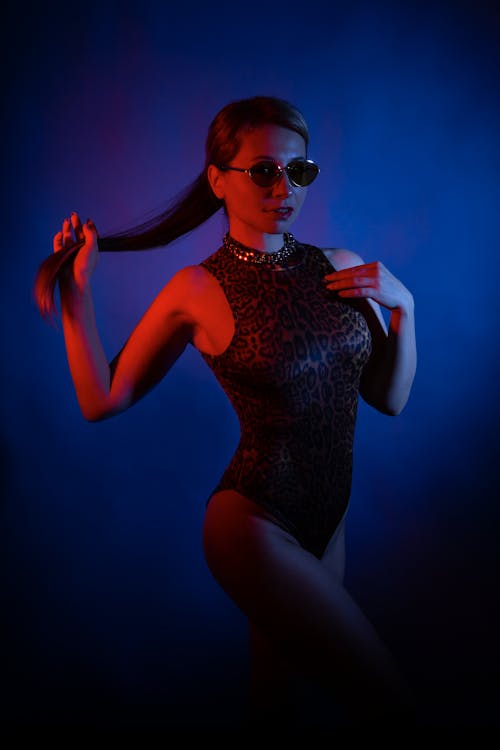 A woman in a black bodysuit and sunglasses