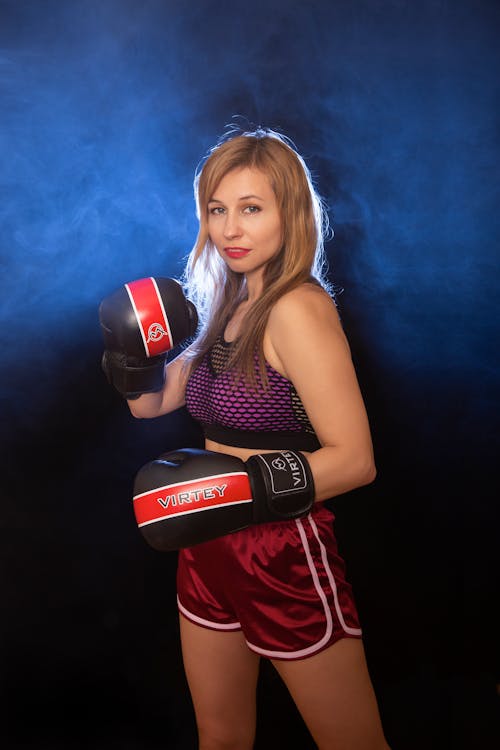 A woman in a red and purple shirt and shorts with boxing gloves