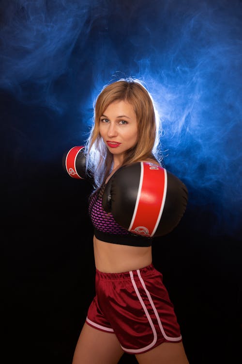 A young woman in boxing shorts and a red shirt