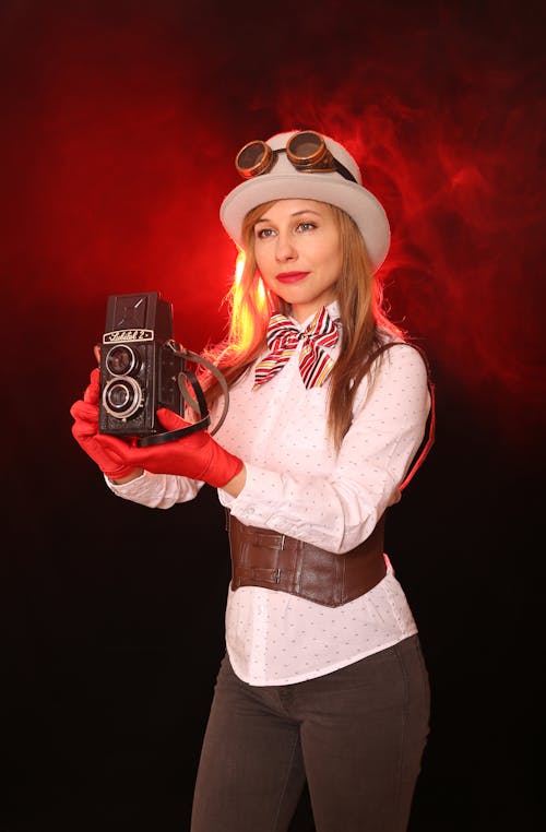 A woman in a hat and gloves holding a camera
