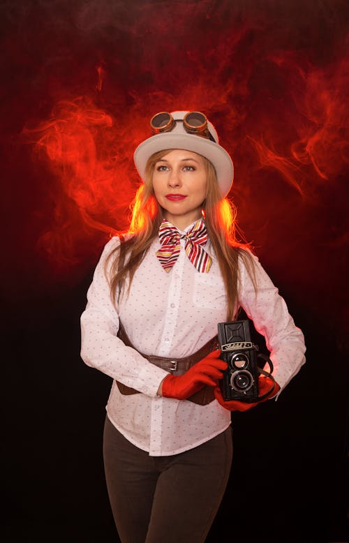 A woman in a hat and gloves holding a camera
