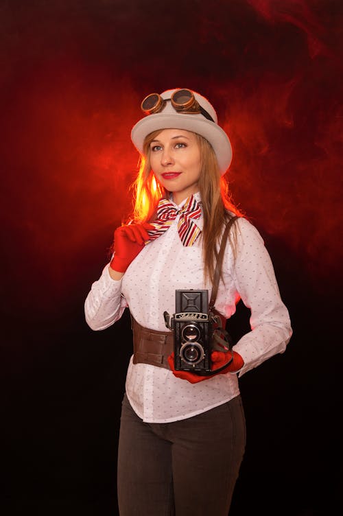 A woman in a hat and gloves holding a camera