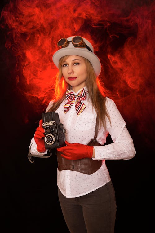 A woman in a hat and gloves holding a camera