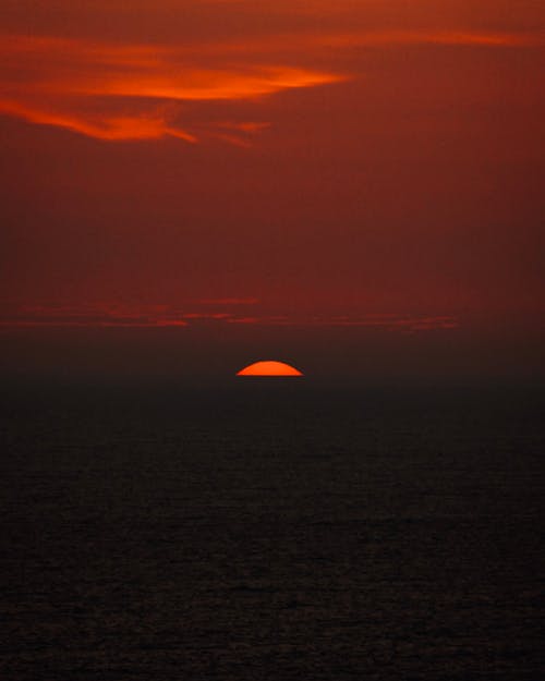 A sunset over the ocean with a red sky