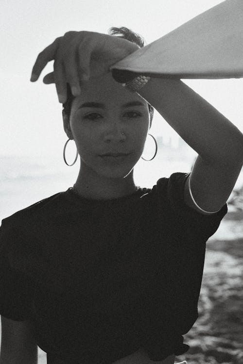 A woman in a black top holding a surfboard