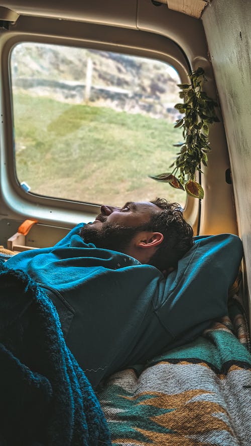 Free A Man Lying on the Bed in a Camper Van and Looking Out the Window  Stock Photo