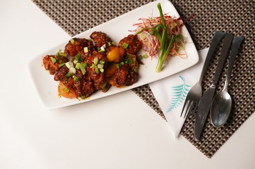 Free Asian dish with vegetables and meat on a patterned mat, garnished with spring onions. Stock Photo