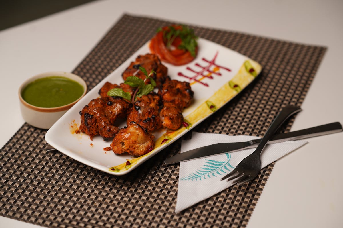 Grilled chicken served with green sauce and fresh herb garnish