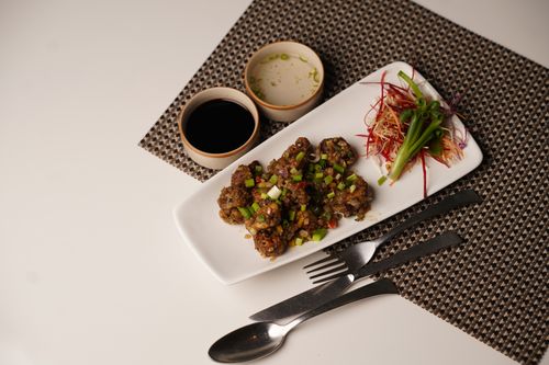 Free Elegantly plated Asian cuisine with fresh vegetables and sauces on a patterned placemat. Stock Photo