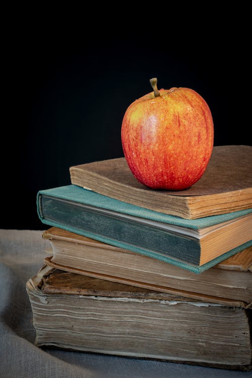 An apple sits on top of a stack of books