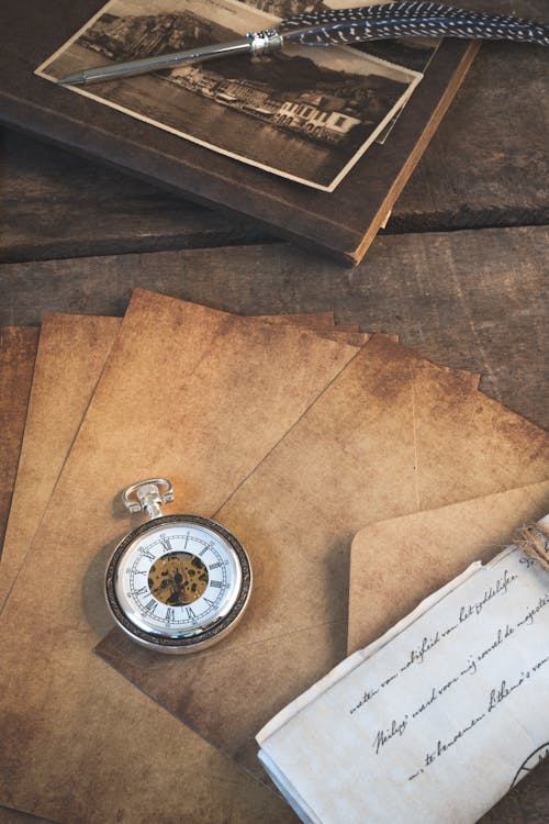 A book with a pocket watch, pen and paper