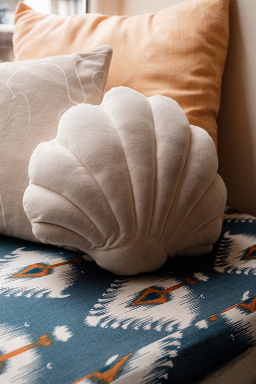 A pillow with a shell on it sits on a couch