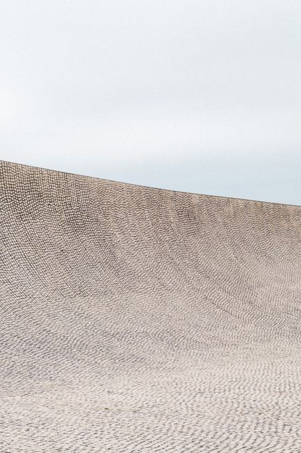 A smooth concrete ramp at an urban skate park in Biarritz, France, under an overcast sky.