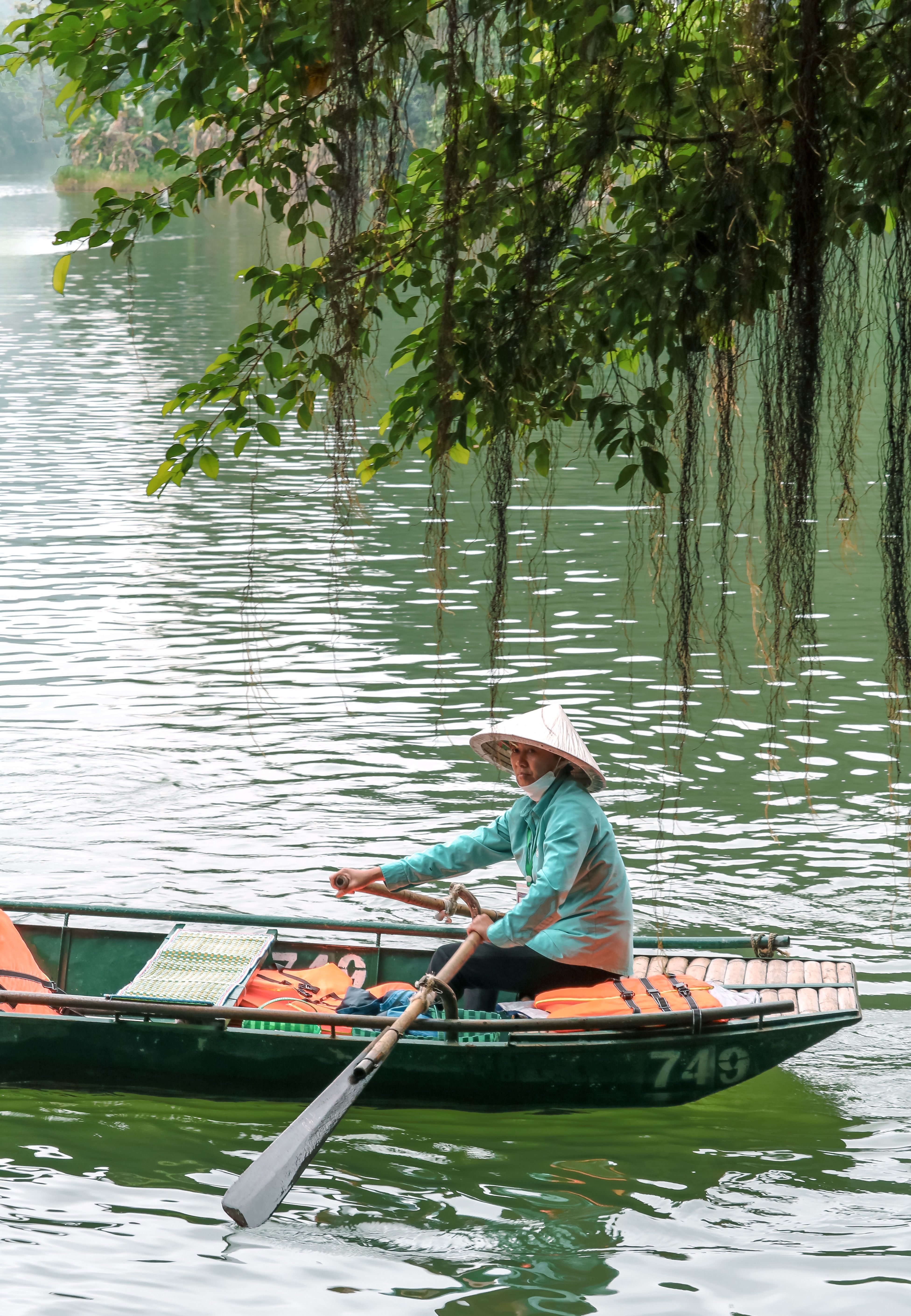 Mujer con sombrero cónico remando en una barca tradicional del Delta del Mekong