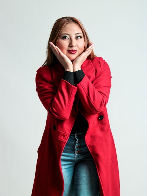 A woman in a red coat is posing for a photo