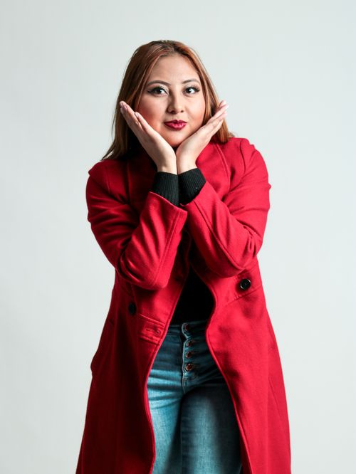 Free Fashionable woman in a red coat posing stylishly in a studio setting. Stock Photo