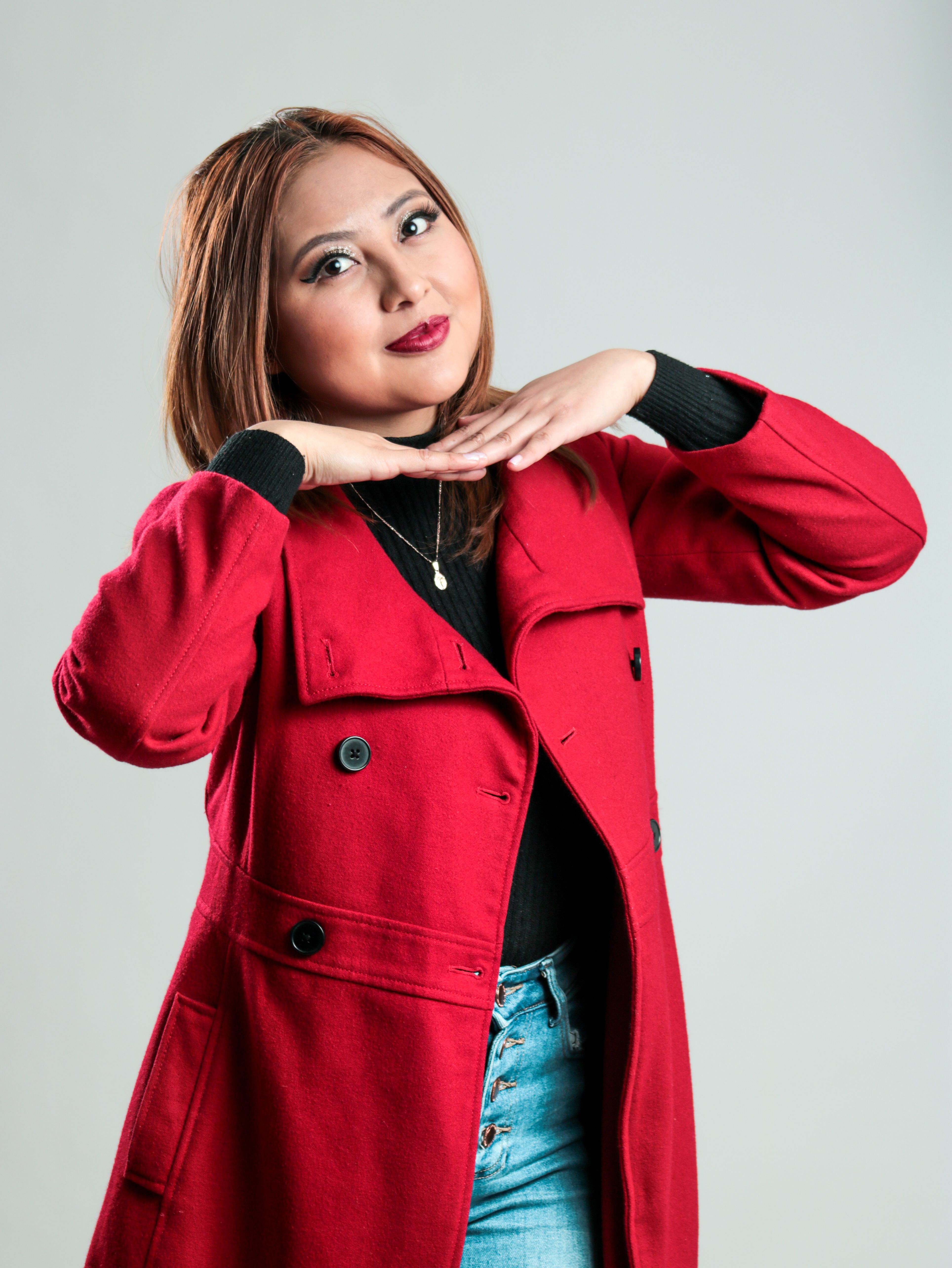 Elegant portrait of a woman posing in a red coat, exuding confidence and fashion-forward style.
