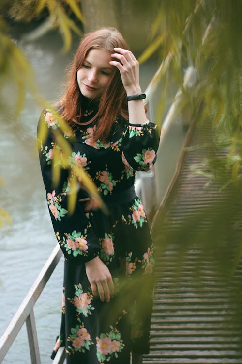 A woman in a floral dress standing on a bridge