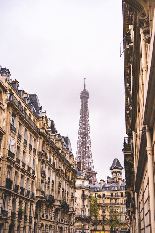 Free Iconic view of the Eiffel Tower framed by classic Parisian architecture under a cloudy sky. Stock Photo