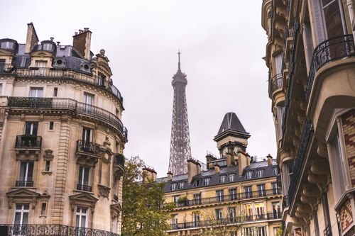 Free Elegant Parisian buildings frame the iconic Eiffel Tower on a cloudy day. Stock Photo