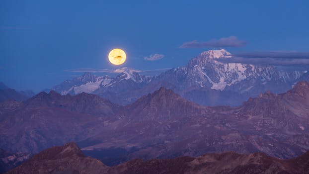 A stunning view of the full moon rising over Mont Blanc with a serene twilight sky backdrop.