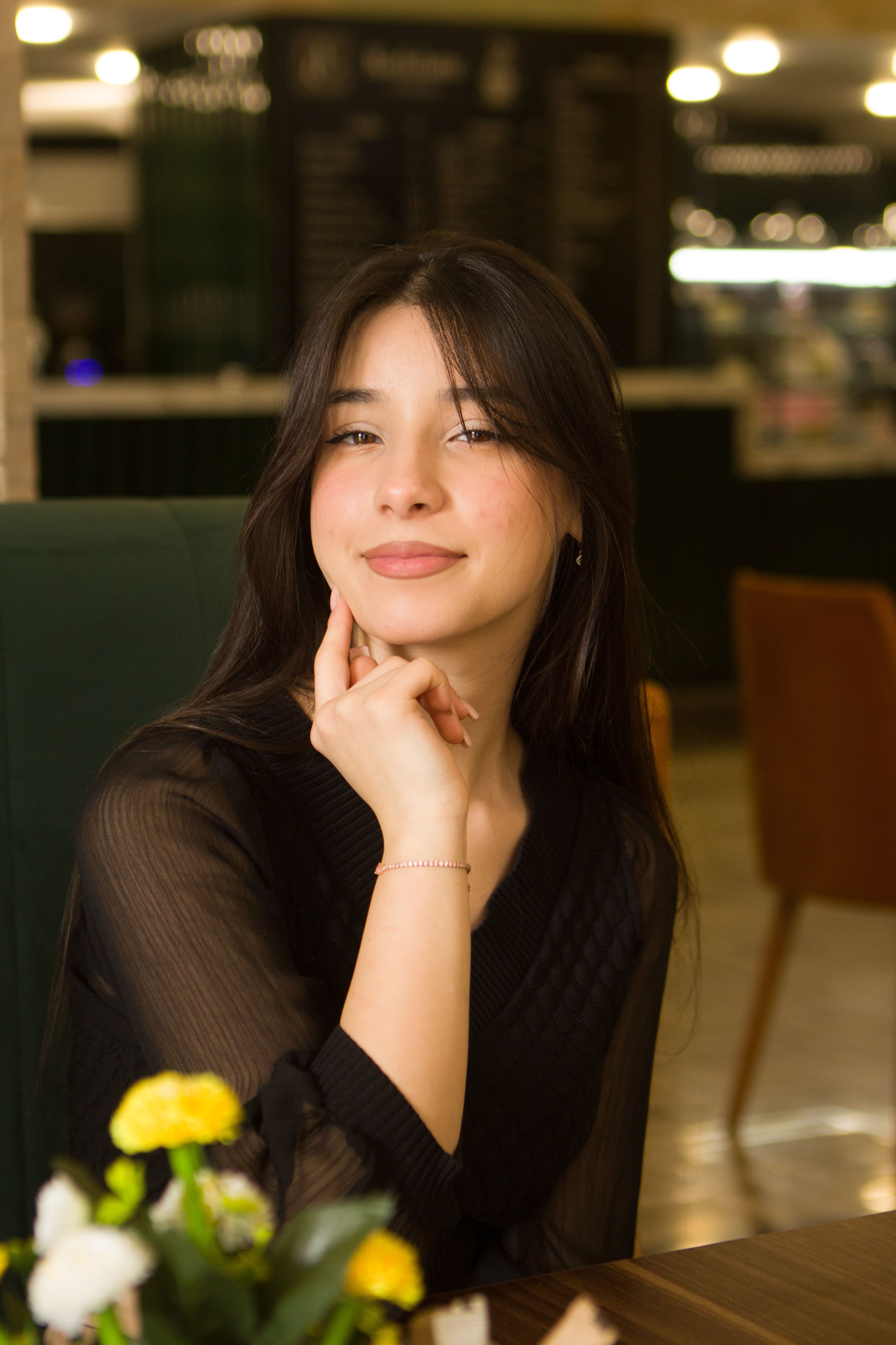 Young woman sitting gracefully in a café, embodying relaxation and warmth.