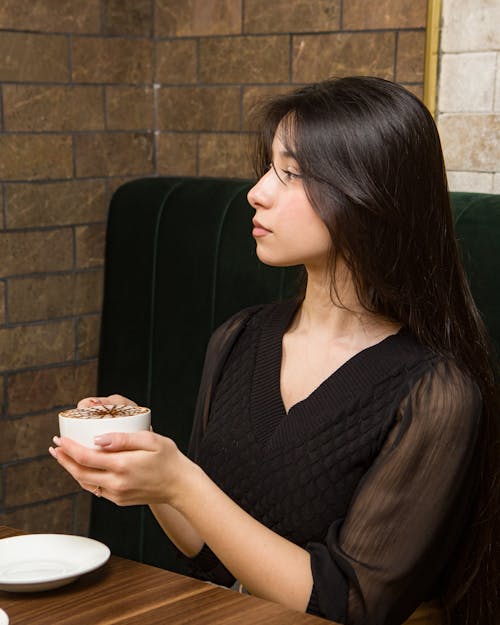 Free Young Woman Drinking Hot Chocolate in a Cafe Stock Photo