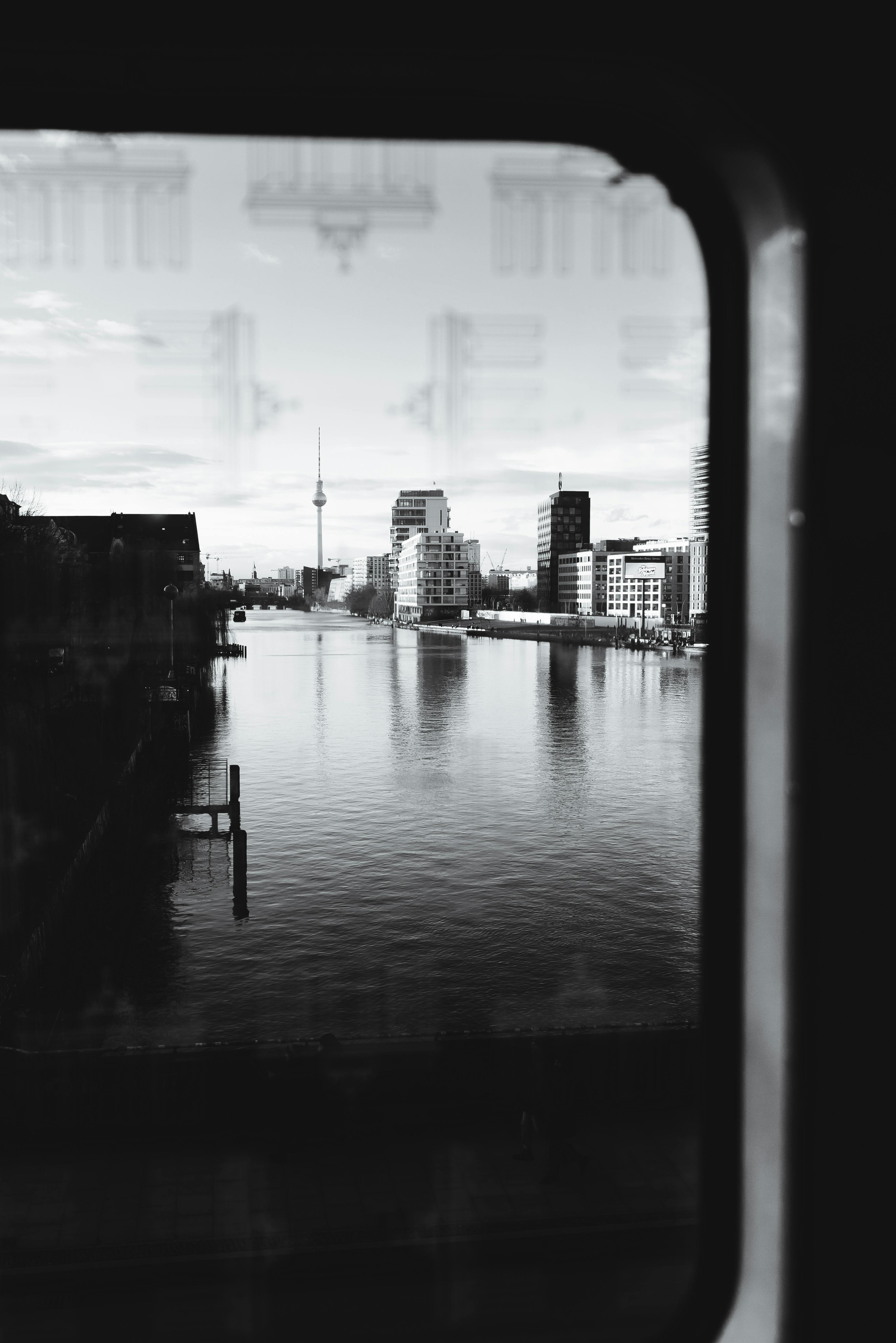 Artistic black and white shot capturing Berlin's skyline and river through a window frame.