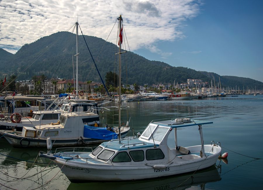 Explore the beautiful coastal town of Fethiye, Türkiye, with its marina and picturesque hills.