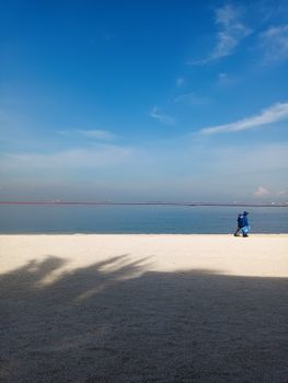 Peaceful beach in Manila with a clear blue sky and lone walker along the shore.