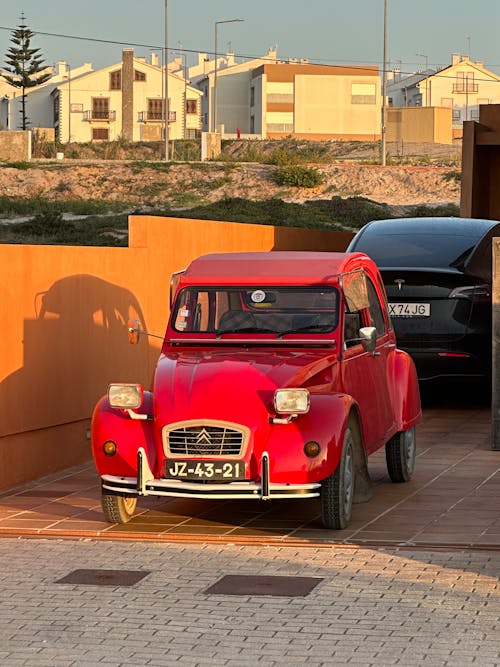 Classic Red Citroen 2CV Parked in the Driveway by a Tesla