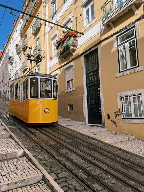 A yellow tram is traveling down a street