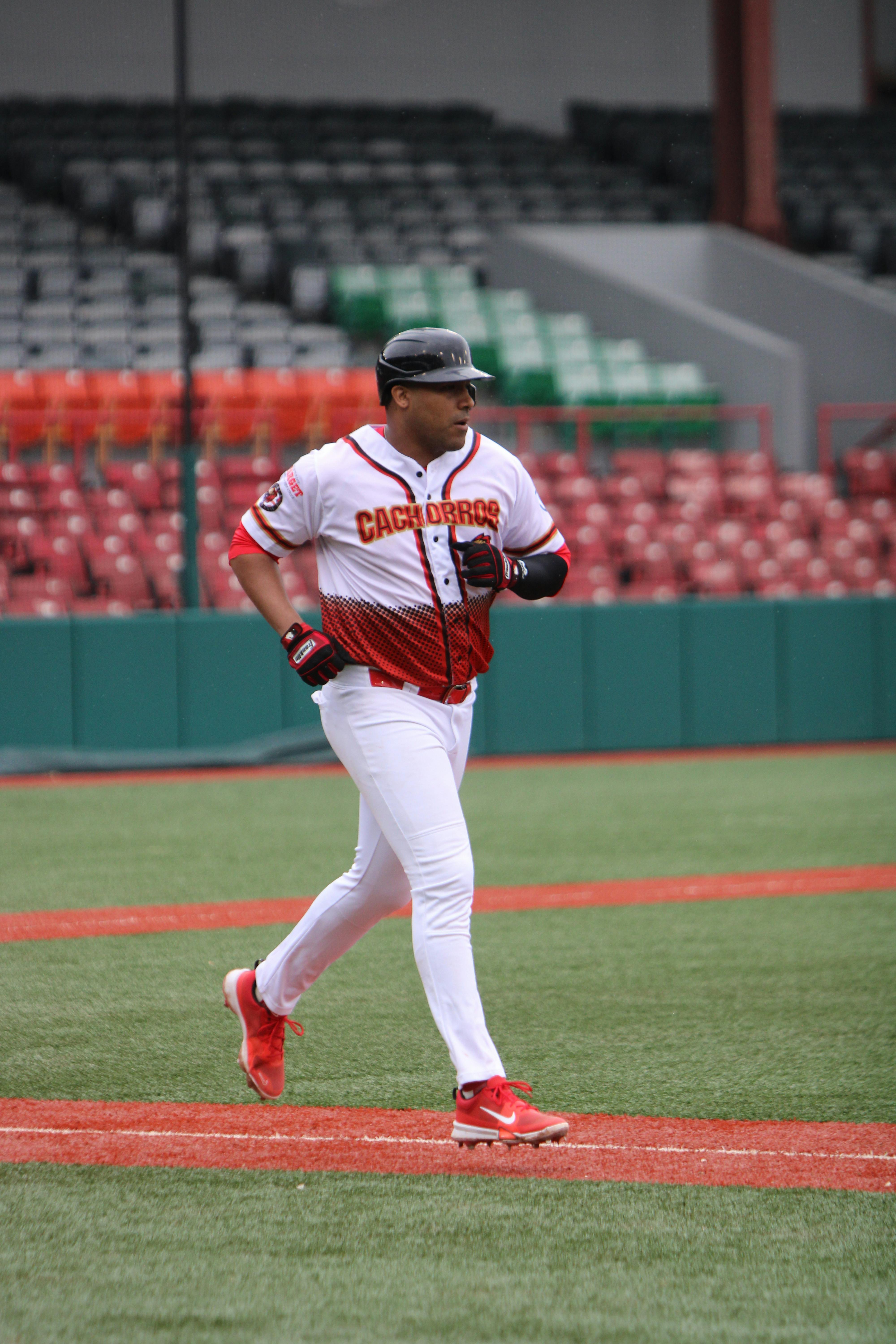A focused baseball player running on the field during a game at a vibrant stadium.