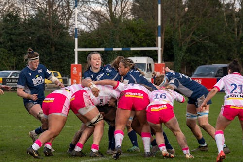 A group of women in pink and blue playing rugby