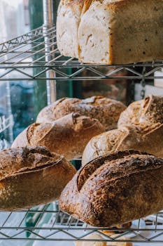 Assorted freshly baked artisan bread loaves displayed on wire shelving in a Buenos Aires bakery.