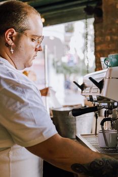 Focused barista in Buenos Aires café using professional espresso machine, mid-action.