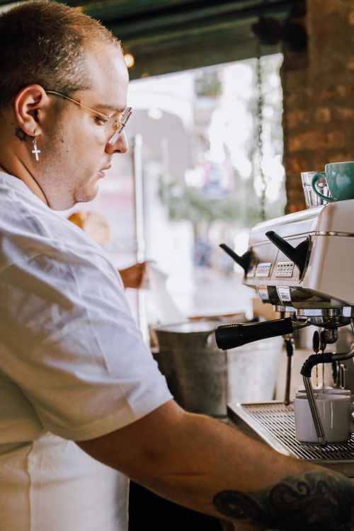 Free Focused barista in Buenos Aires café using professional espresso machine, mid-action. Stock Photo
