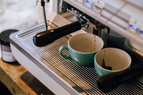 Free Close-up view of an espresso machine pouring into cups, capturing fresh coffee in Buenos Aires. Stock Photo