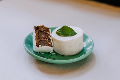 A green plate with a piece of cake and mint leaves