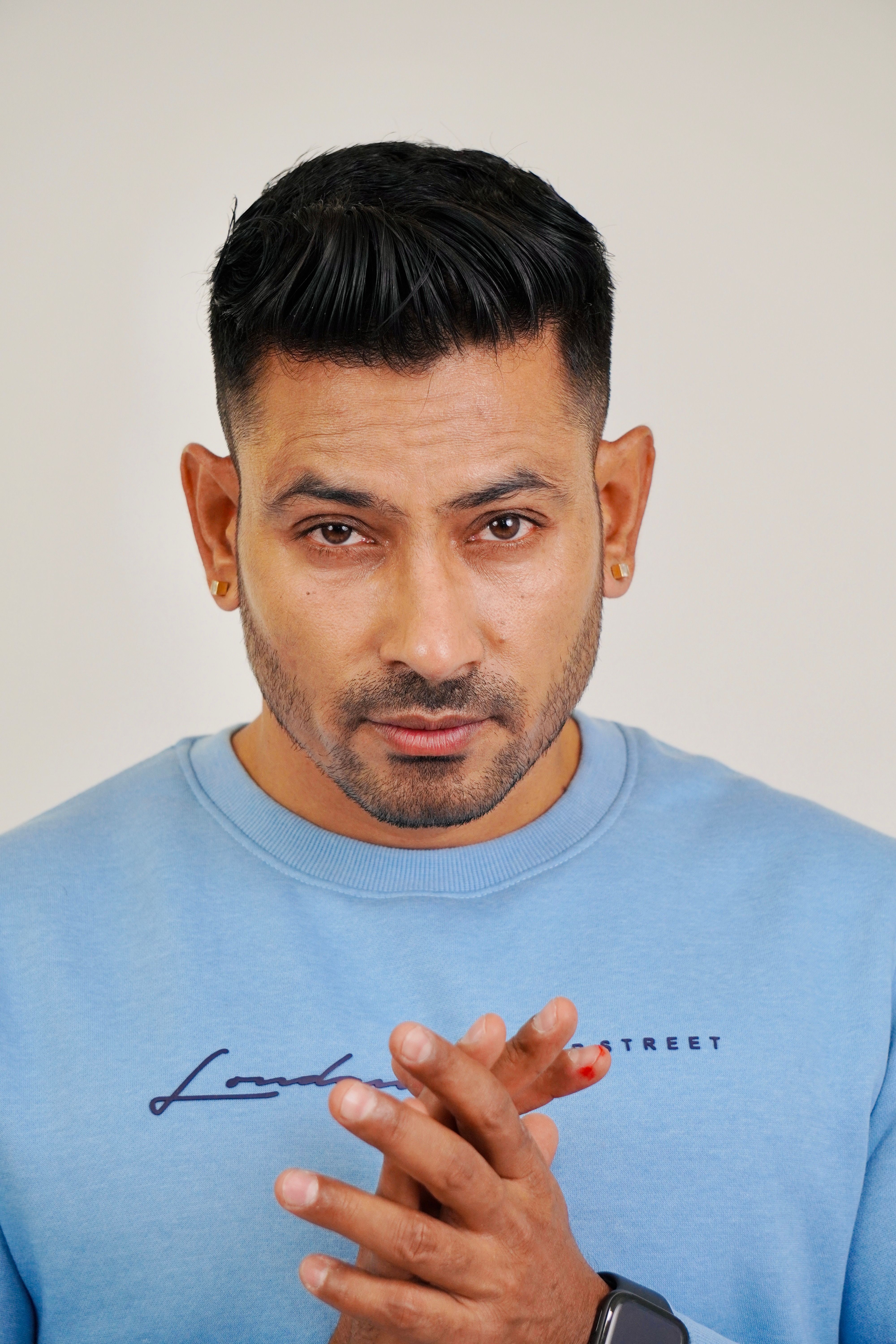 Portrait of a confident man with short hair wearing a blue sweater in a studio setting.
