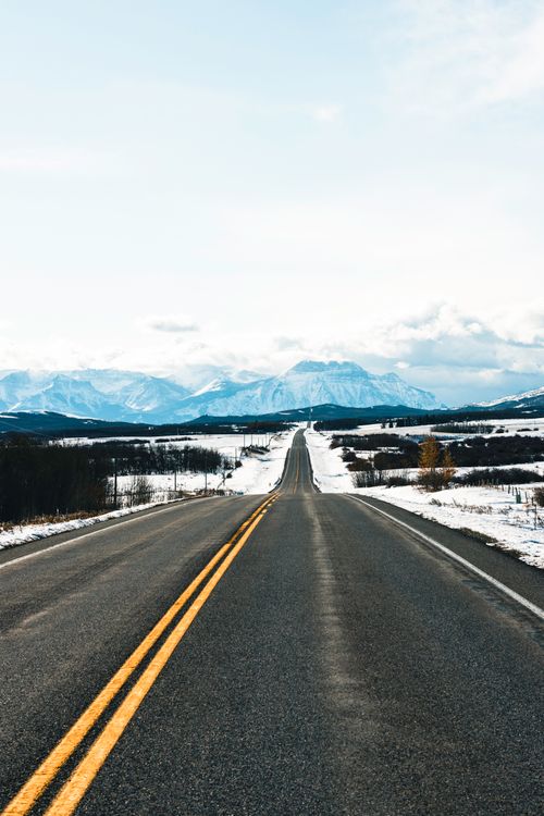 Free A picturesque highway through snowy plains and distant mountains in Waterton Park, Alberta, Canada. Stock Photo