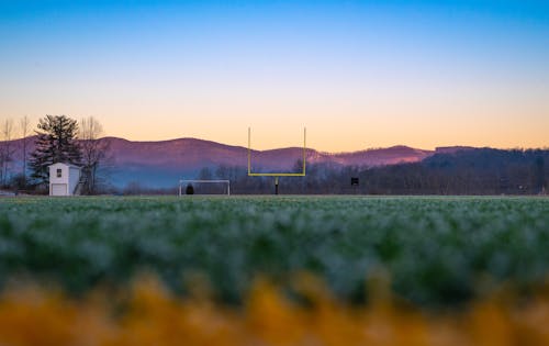 A football field in the middle of a field with mountains in the background