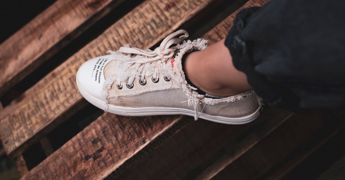 Frayed beige sneaker on wooden pallet evokes rustic urban style.