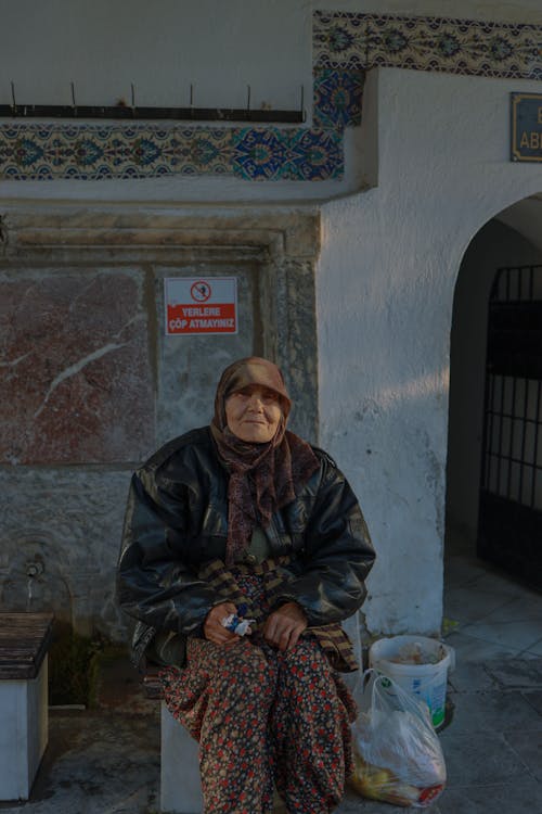 A woman sitting on a bench in front of a building