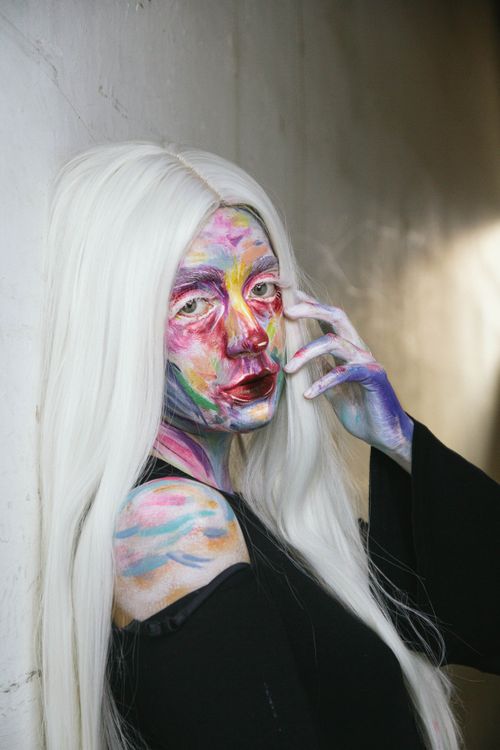 Free Expressive portrait of a woman with vibrant and colorful face makeup, showcasing artistic creativity. Stock Photo