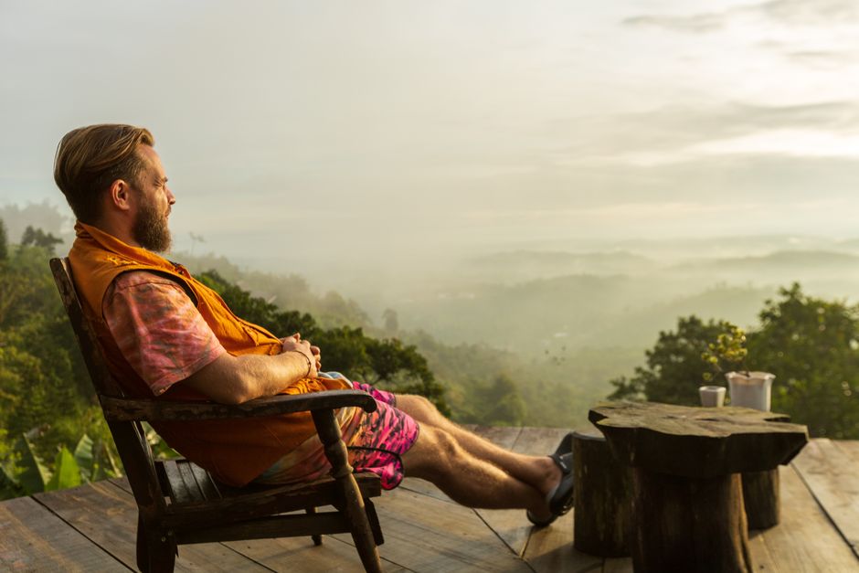 Man relaxing on a deck overlooking a misty mountain landscape at sunrise. Man relaxing on a deck overlooking a misty mountain landscape at sunrise.