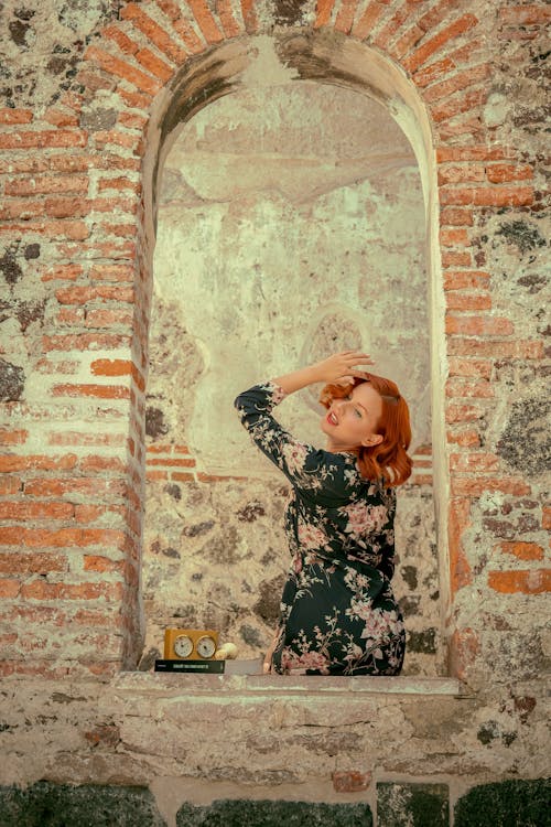 A woman in a floral dress looking out of a window